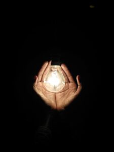 A pair of hands in the darkness cradling a GLOWING light. Write Good.