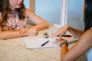 Two Women discussing a paper and providing feedback. Hopefully not Negative Feedback.