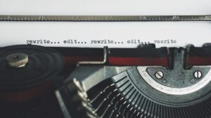 A old style typwriter with paper loaded with the words, "Rewrite, edit, rewrite, edit, rewrite."
